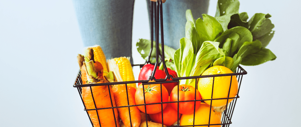 Person holding grocery basket filled with food