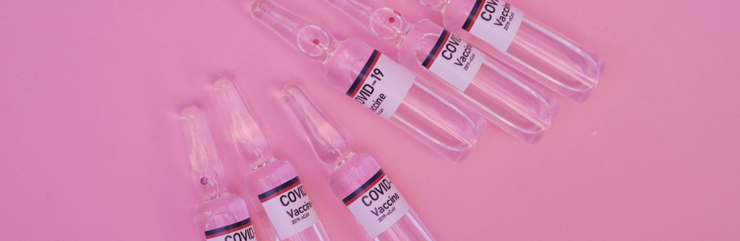 Various covid test bottles on a pink background