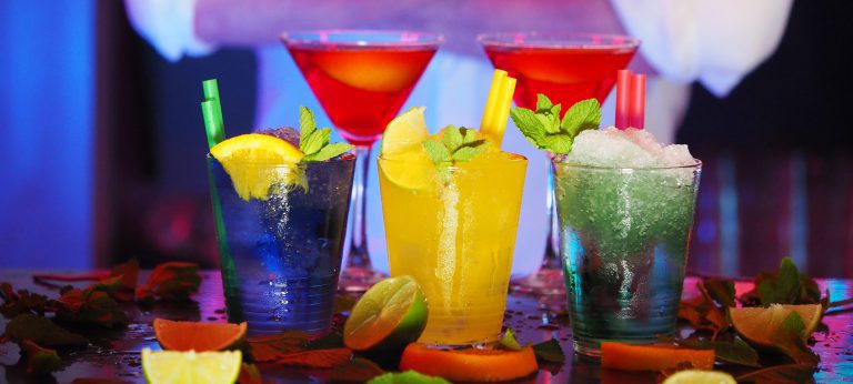 Various colorful mixed alcoholic drinks on a counter