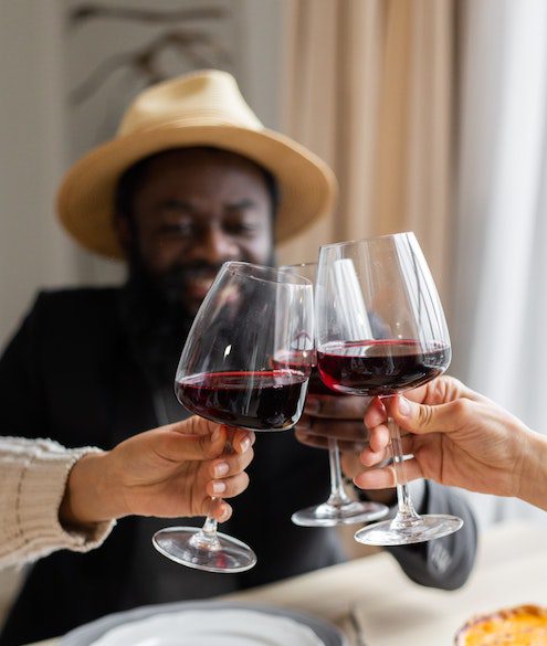 Black man with hat drinking wine with friend