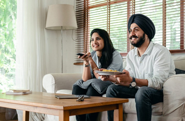 Indian couple sitting on couch watching TV