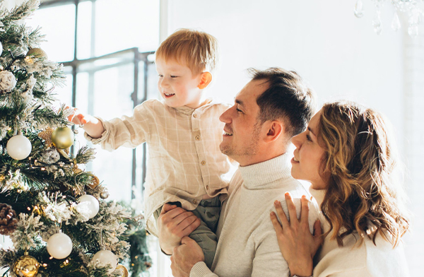 Family with young son decorating holiday tree