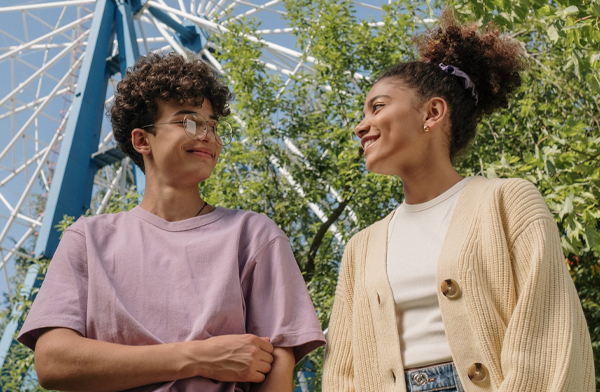 Two black women smiling at each other under ferris wheel