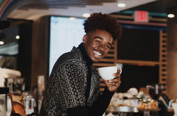Happy young black man smiling at bar