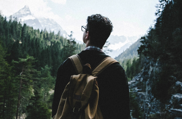 Young man with backpack hiking in mountains