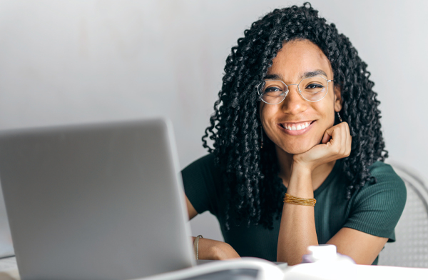 Smiling black woman sitting in front of silver laptop
