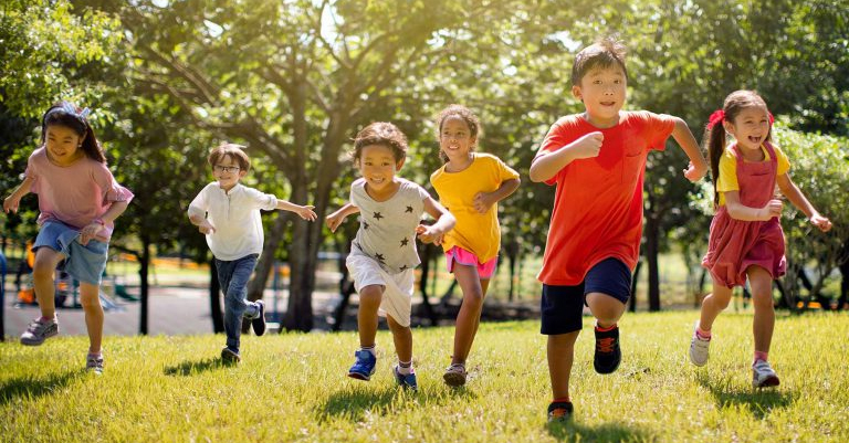 multicultural kids running through grass field