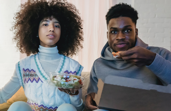 young black couple watching tv and eating popcorn
