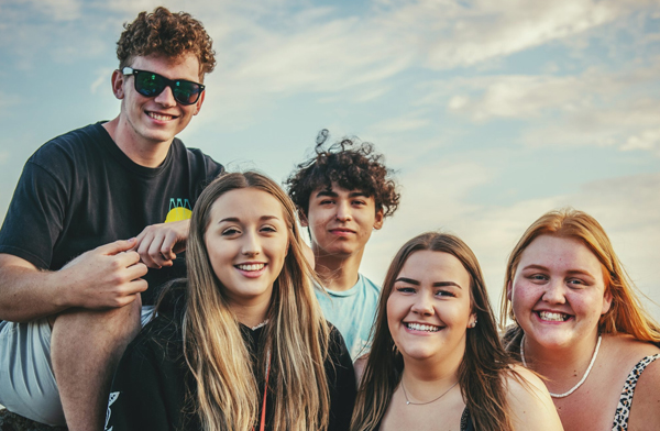 Group of Gen Z men and women smiling at sunset