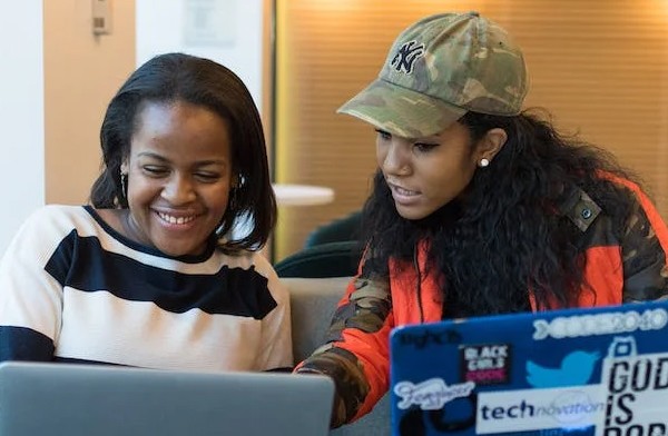Two gen x black women looking at their laptop computers