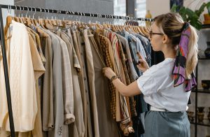 Blonde woman looking through rack of clothing at store
