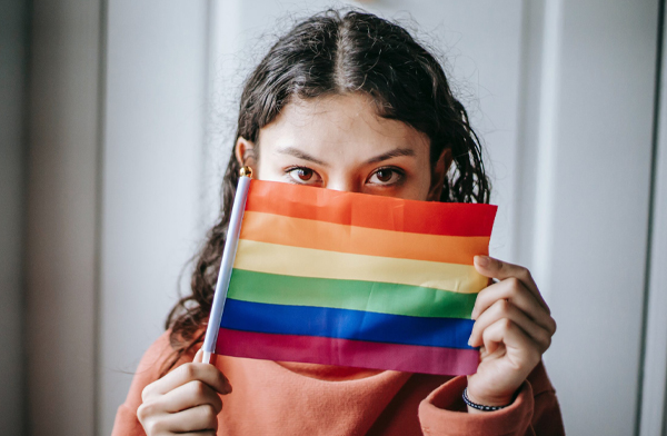 Young woman holding up LGBTQ+ pride flag