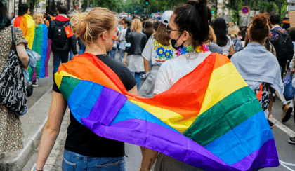 two gen z lgbtq+ women draped in a pride flag
