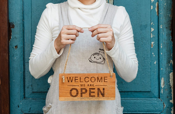 Asian woman small business owner holding a welcome sign