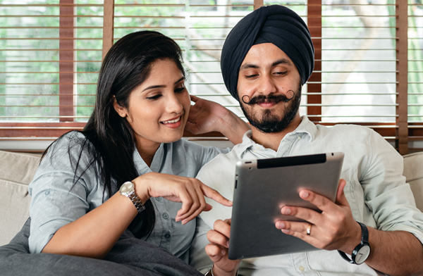 Indian couple looking at tablet computer on couch