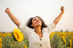 Black woman celebrating victory in a field of sunflowers