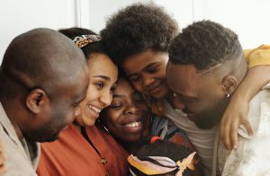 Black family hugging and smiling in their kitchen