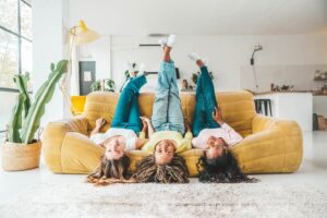 Three Gen Z Hispanic women laughing together on a couch