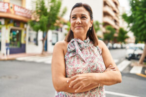 Gen X Hispanic woman smiling while standing confidently near a city street