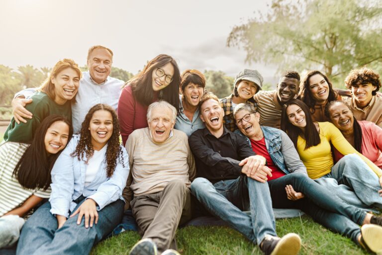 Multigenerational, multicultural group of people sitting together, posing for a photo