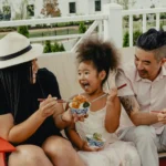 Multicultural family enjoying food outside on a bench