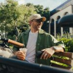 Hispanic man holding a coffee and sitting on a park bench