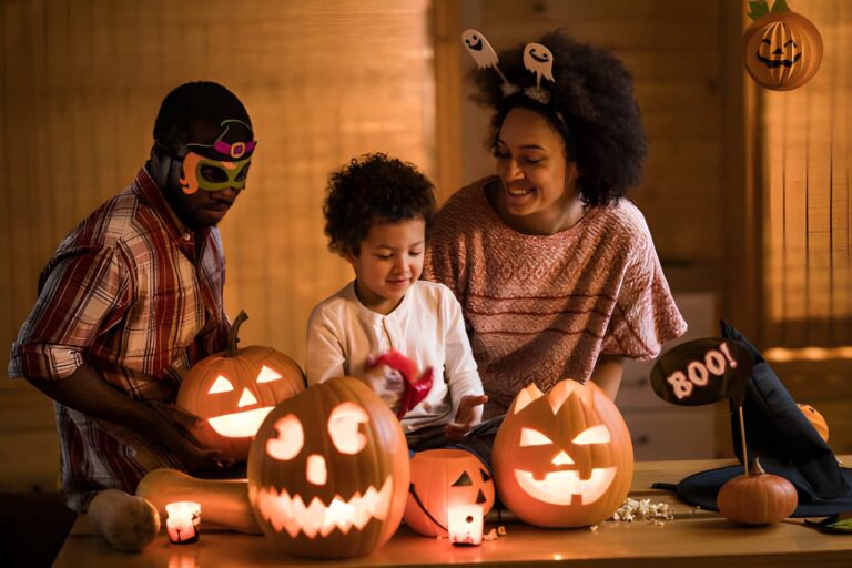 Family dressed up for Halloween with carved, lit up pumpkins on the table in front of them